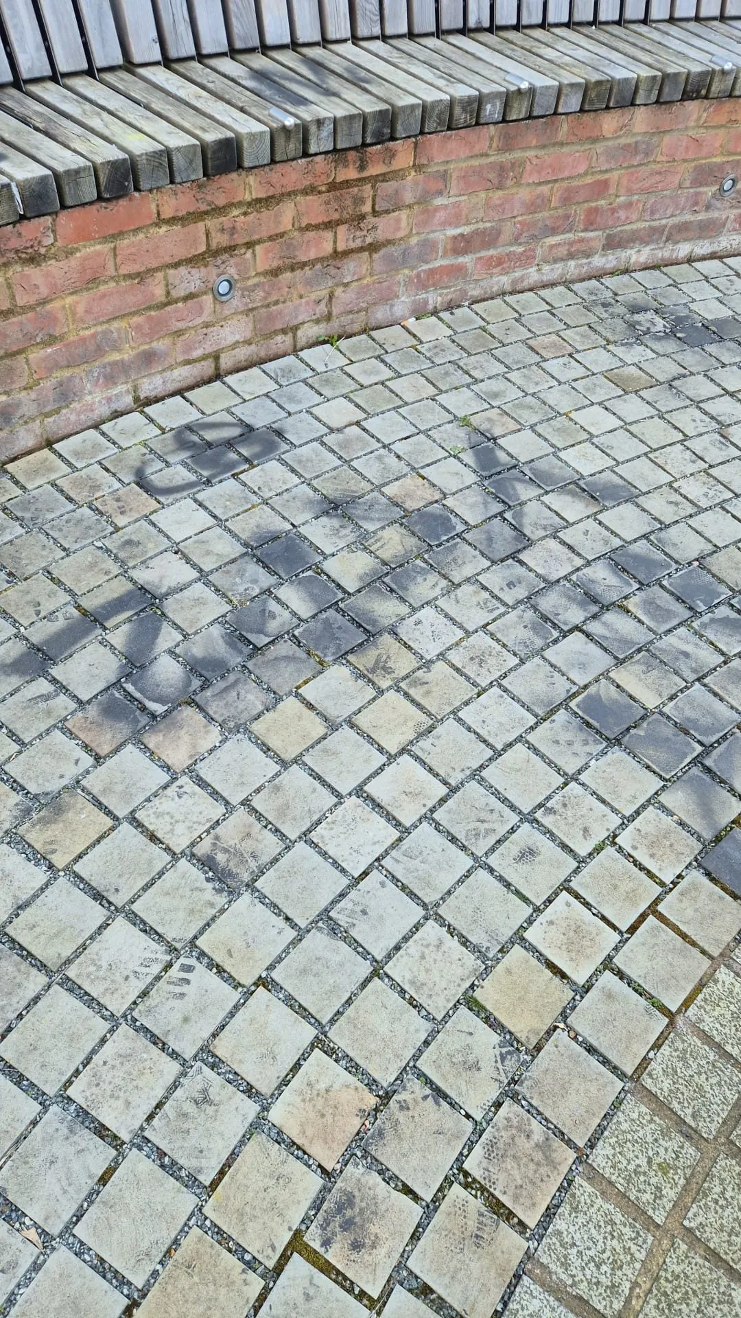 Block paving with graffiti staining on brick wall before professional graffiti removal
