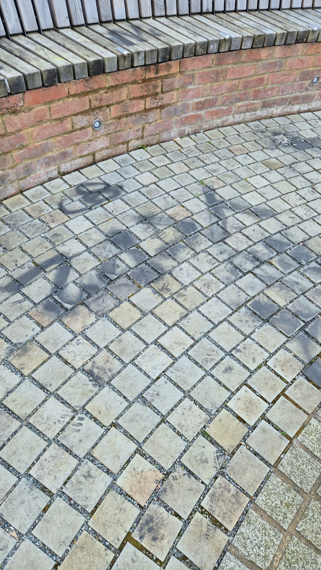 Block paving with graffiti staining on brick wall before professional graffiti removal