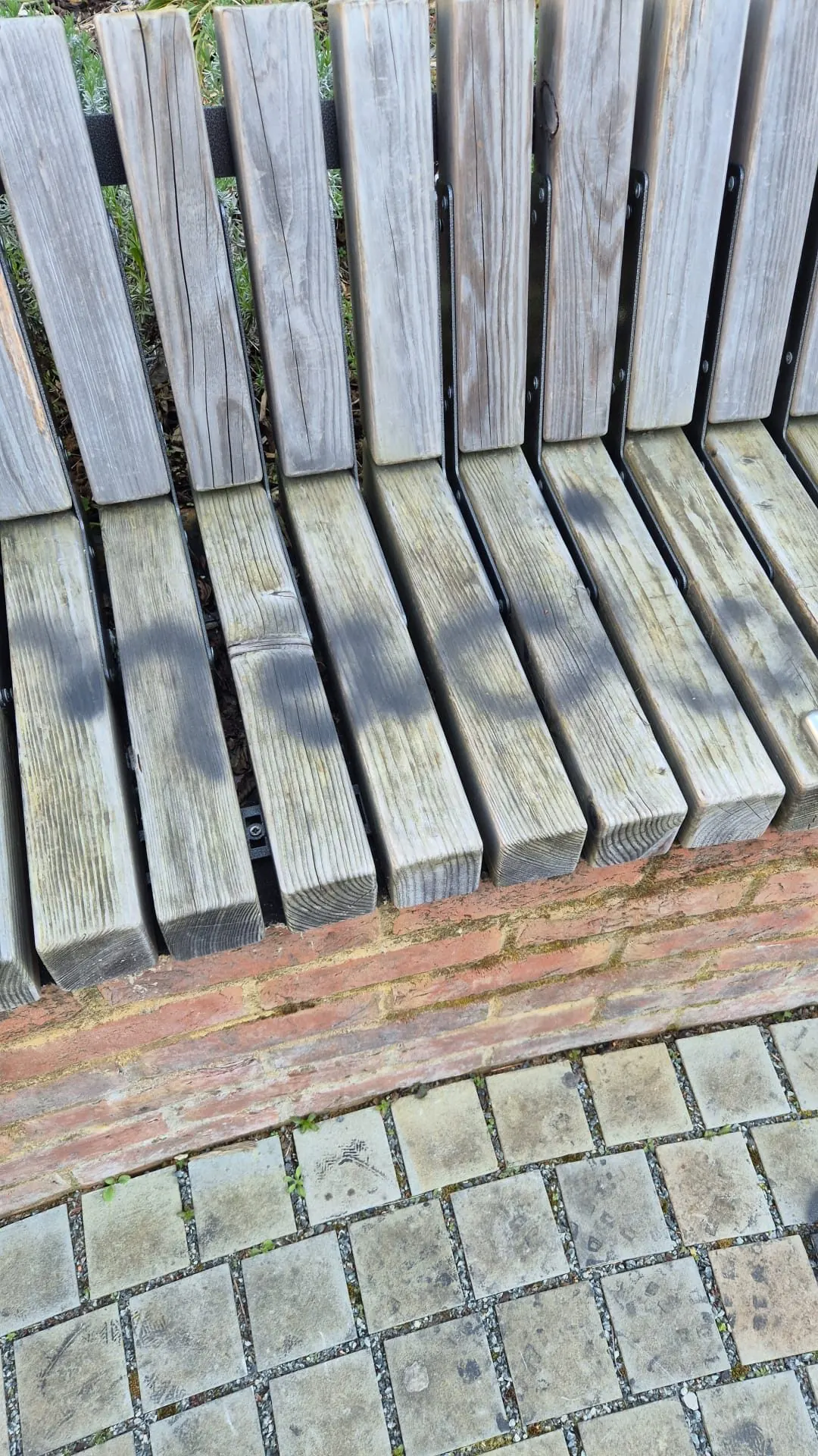 Close-up of wooden bench and brick wall with graffiti damage before removal