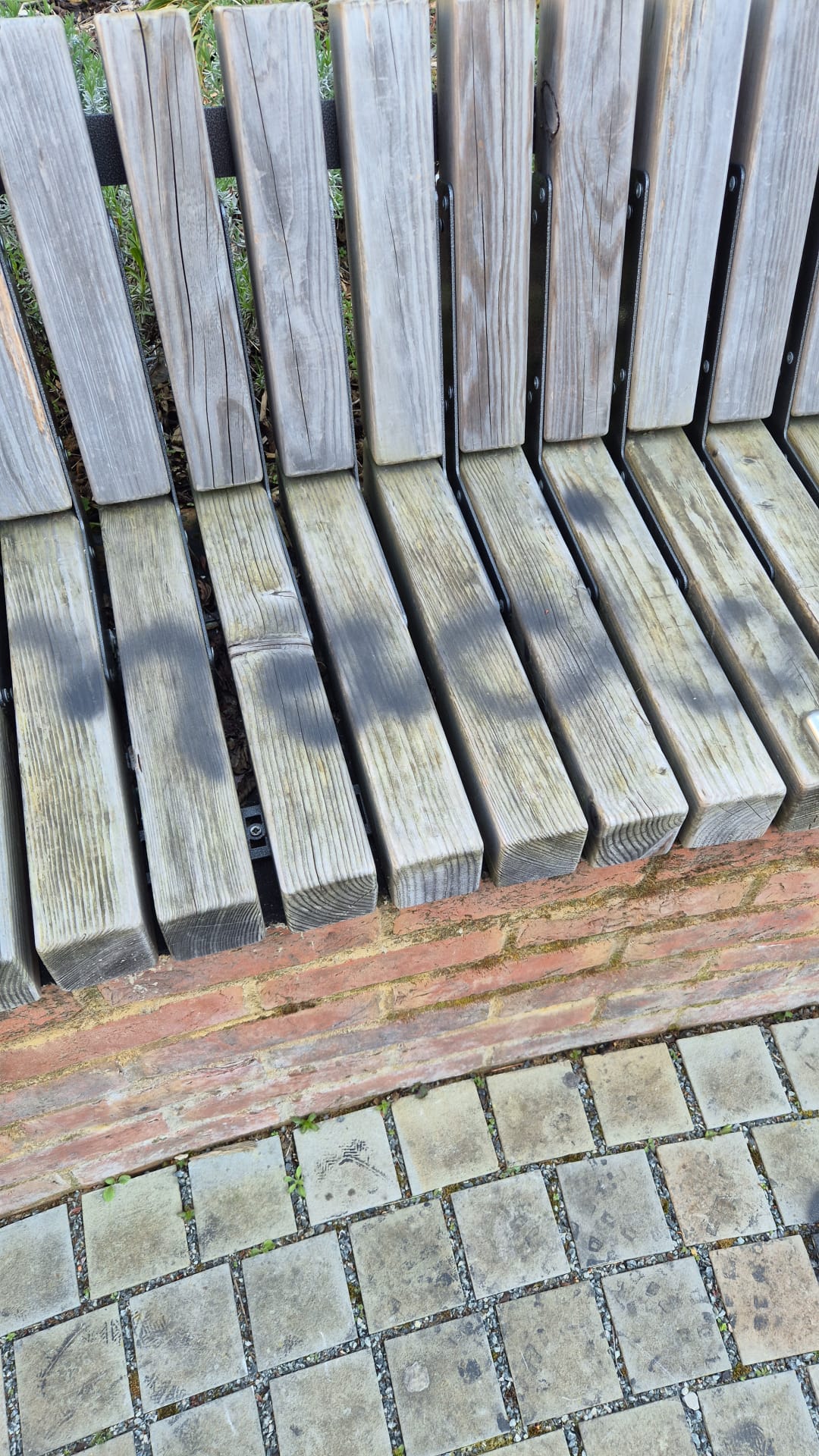 Close-up of wooden bench and brick wall with graffiti damage before removal
