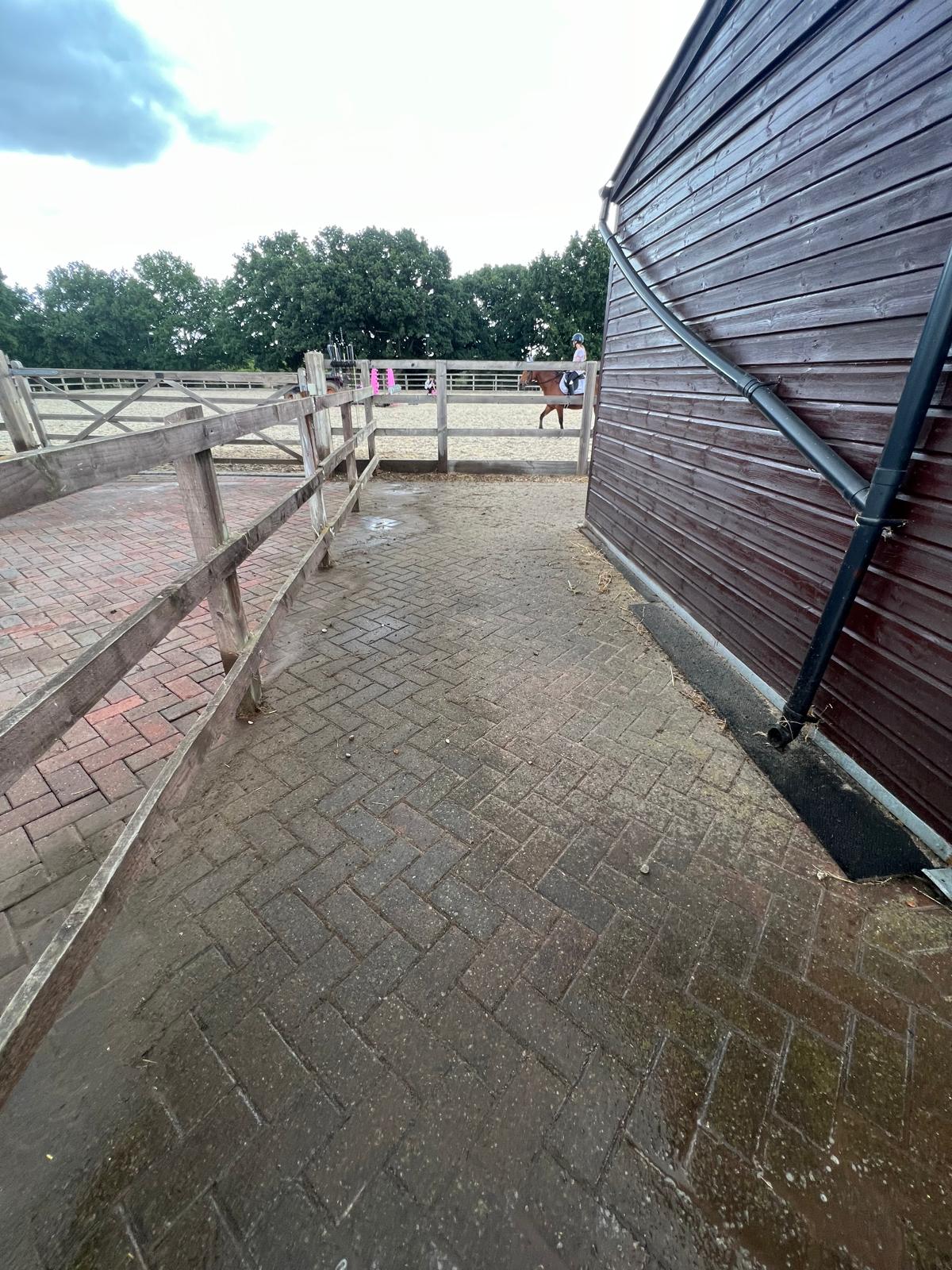 Dirty block paving corner area at stables covered in moss and grime before cleaning