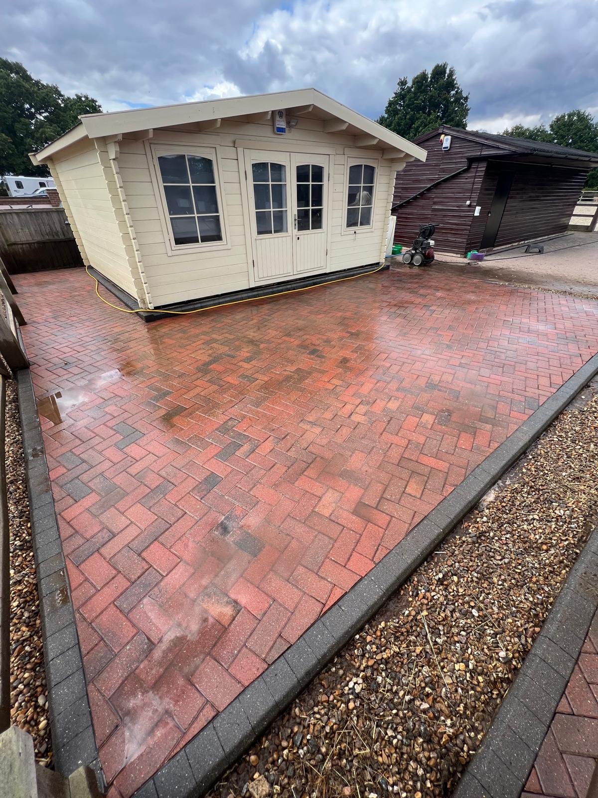 Clean block paving driveway outside cabin restored after professional pressure washing