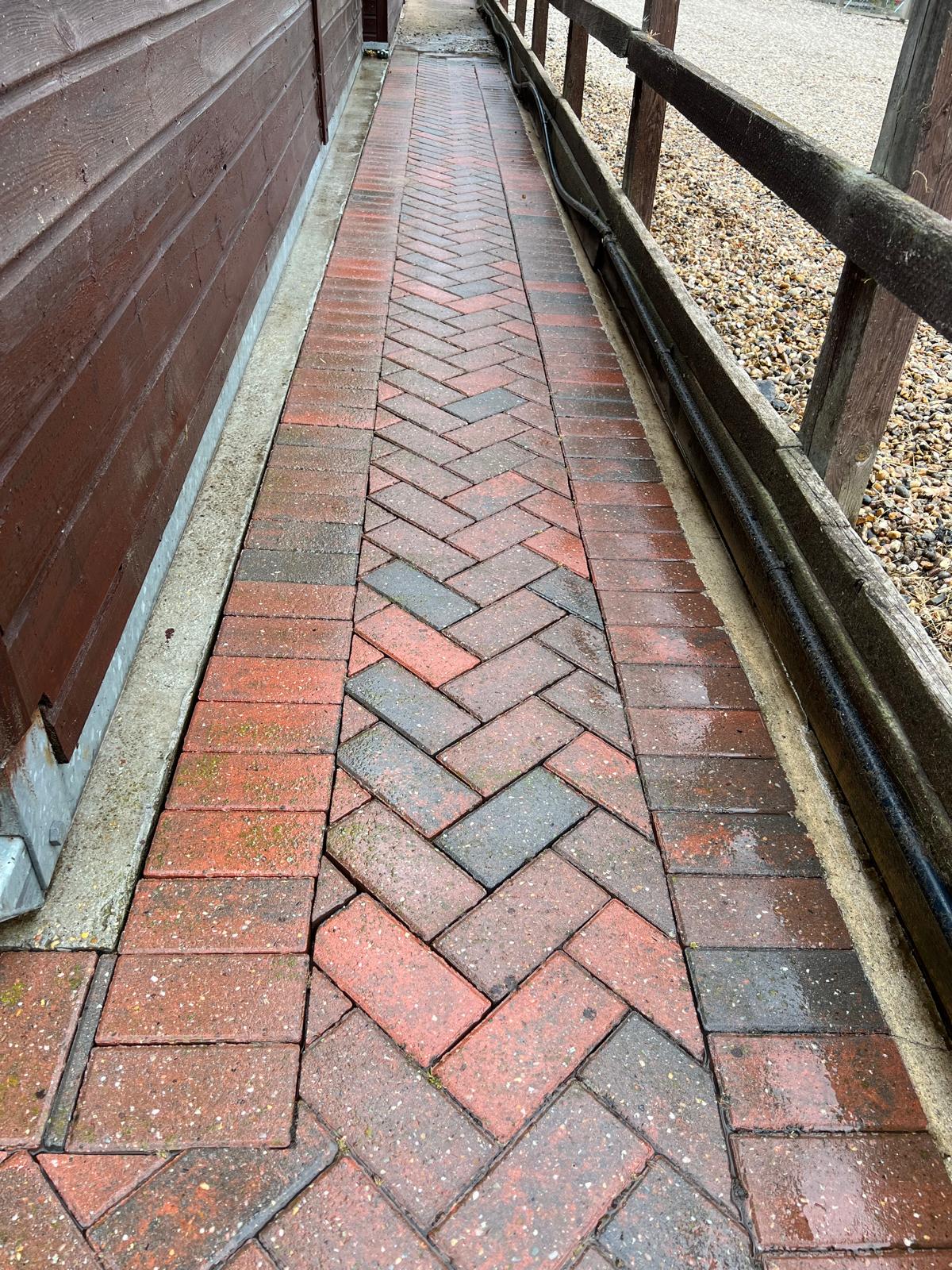 Clean herringbone block paving stable path restored to original red colour after professional cleaning
