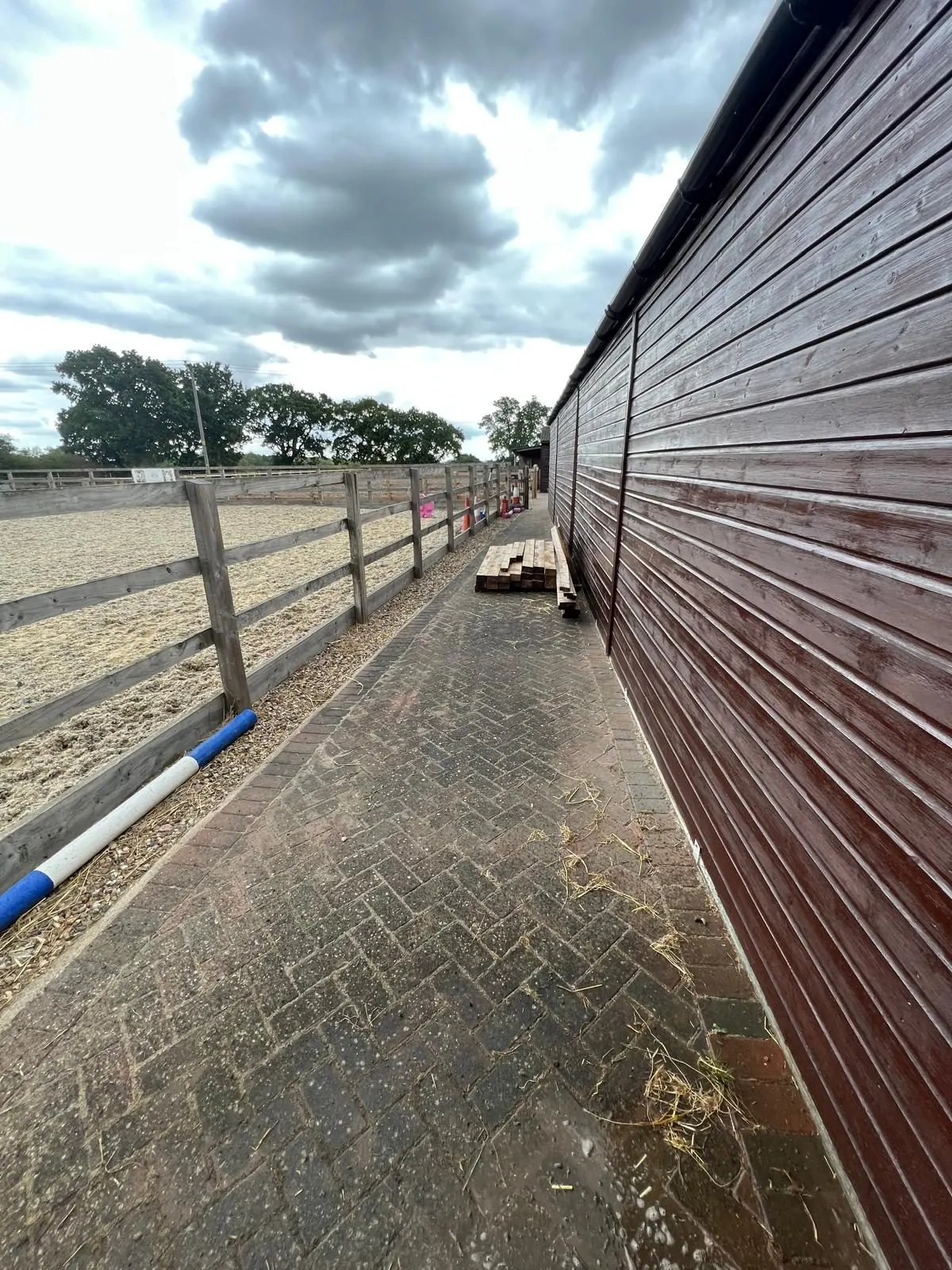 Moss and dirt covered block paving yard at equestrian stables before professional cleaning