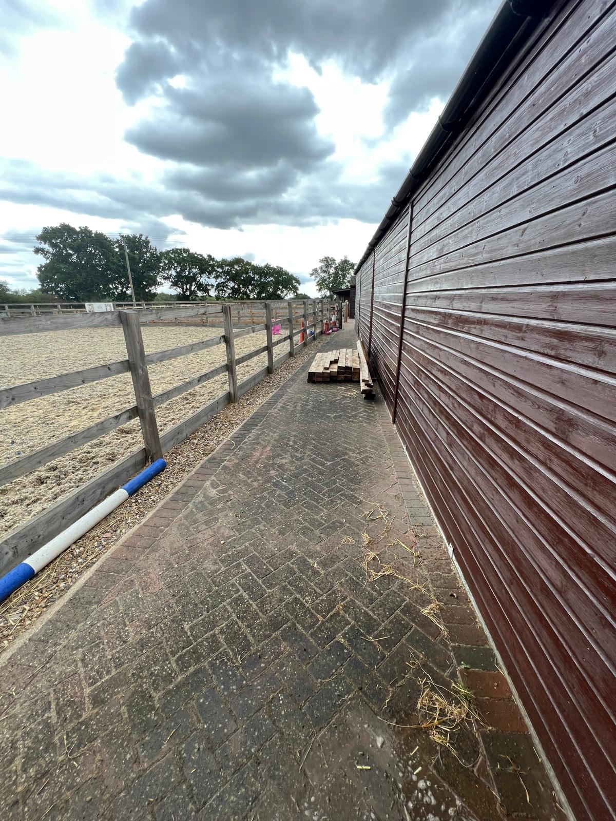 Moss and dirt covered block paving yard at equestrian stables before professional cleaning
