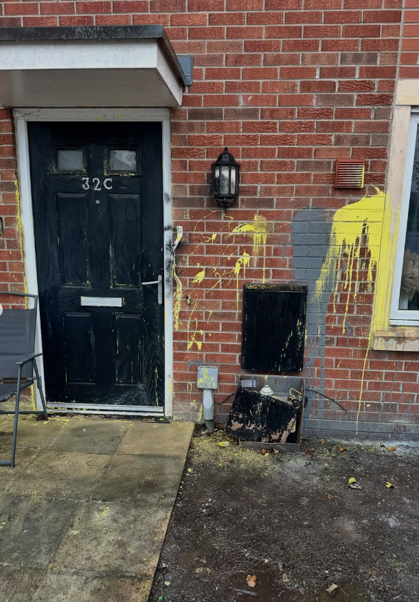 Yellow graffiti sprayed across brick house wall before professional graffiti removal