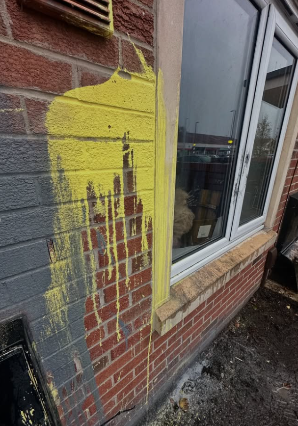 Close-up of yellow graffiti paint on brick wall before removal treatment