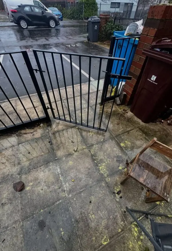 Yellow paint splashes across patio slabs before exterior graffiti cleanup
