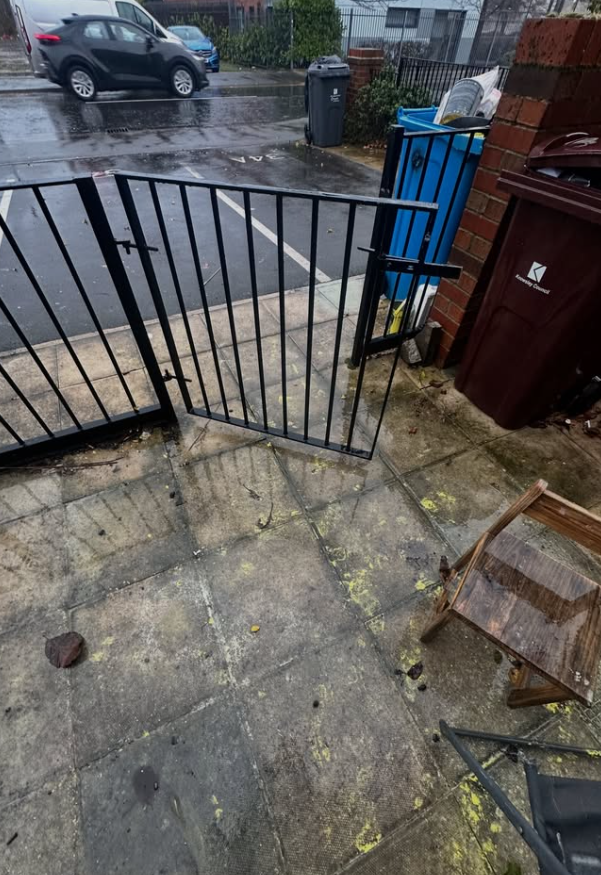 Yellow paint splashes across patio slabs before exterior graffiti cleanup