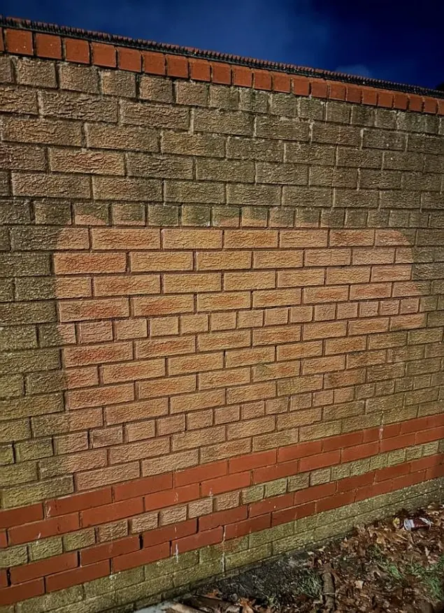 Boundary brick wall showing a paint removal test patch during exterior restoration