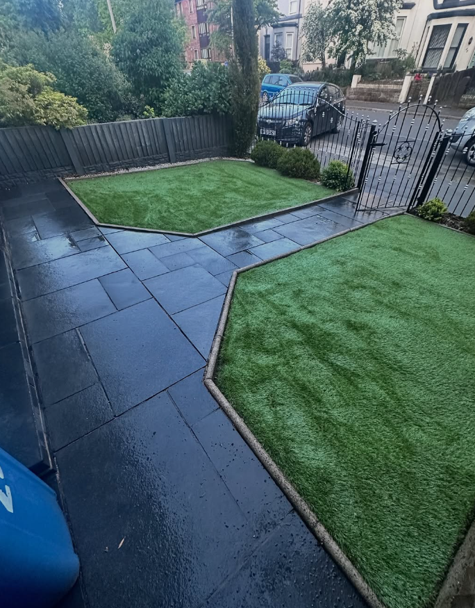 Dark slate patio professionally cleaned with crisp edges alongside green lawn in Wirral
