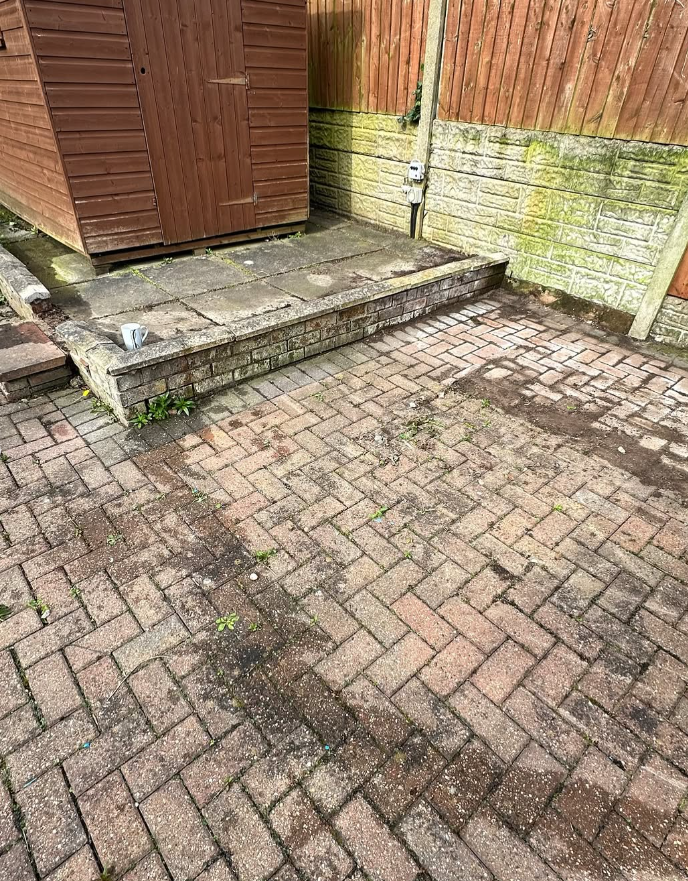 Block paved patio and retaining wall before steam jet washing