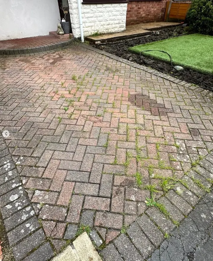 Block paved driveway before restoration with weeds growing between joints