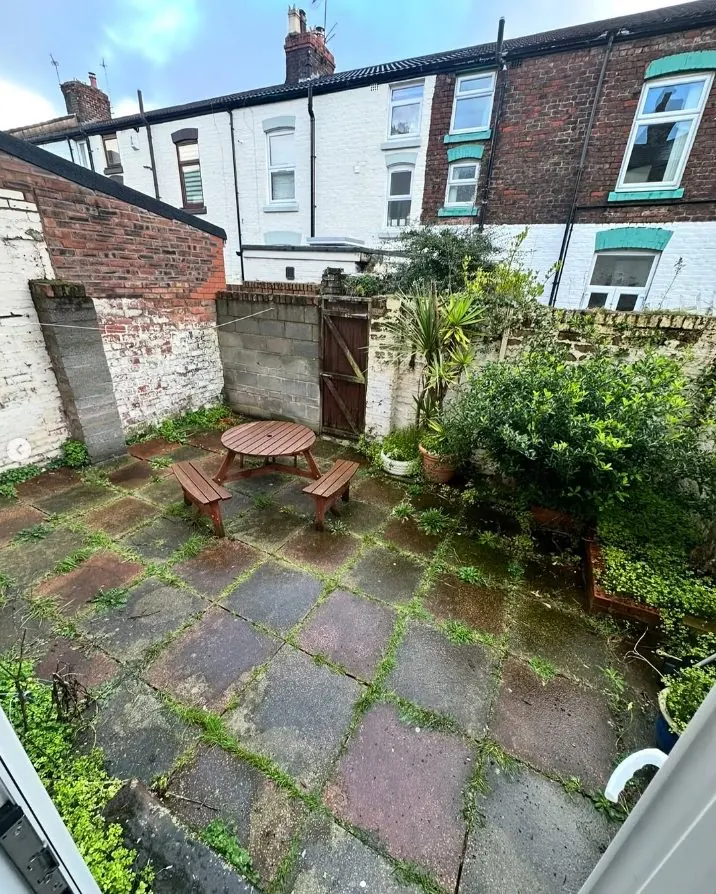 Small courtyard patio before cleaning with moss between paving slabs