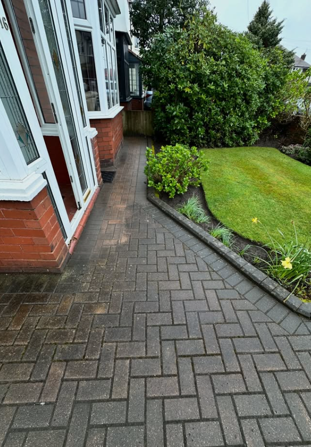 Dirty block paving path with moss growth before professional cleaning