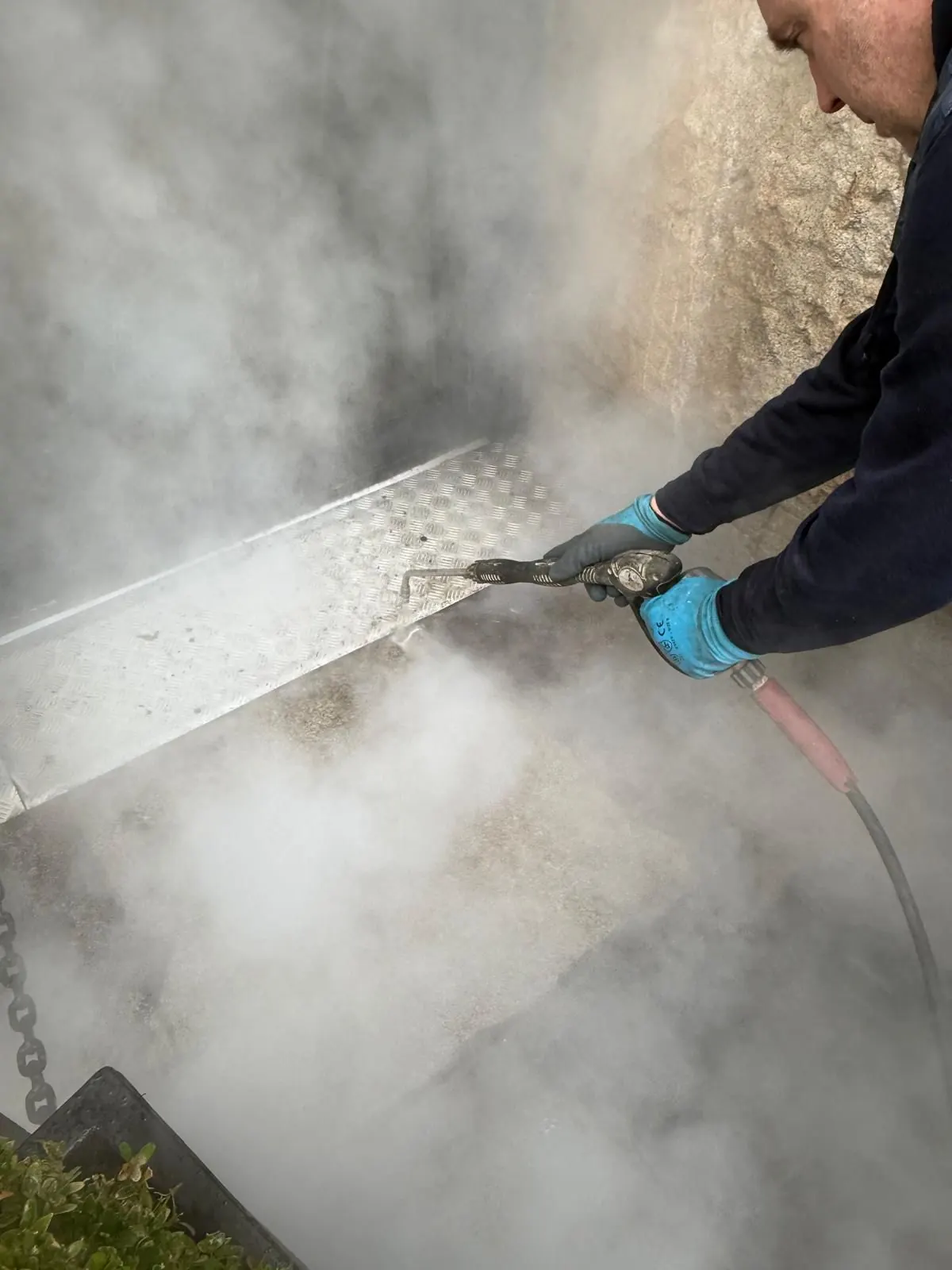 Operative using DOFF steam lance to clean soiled stone surface